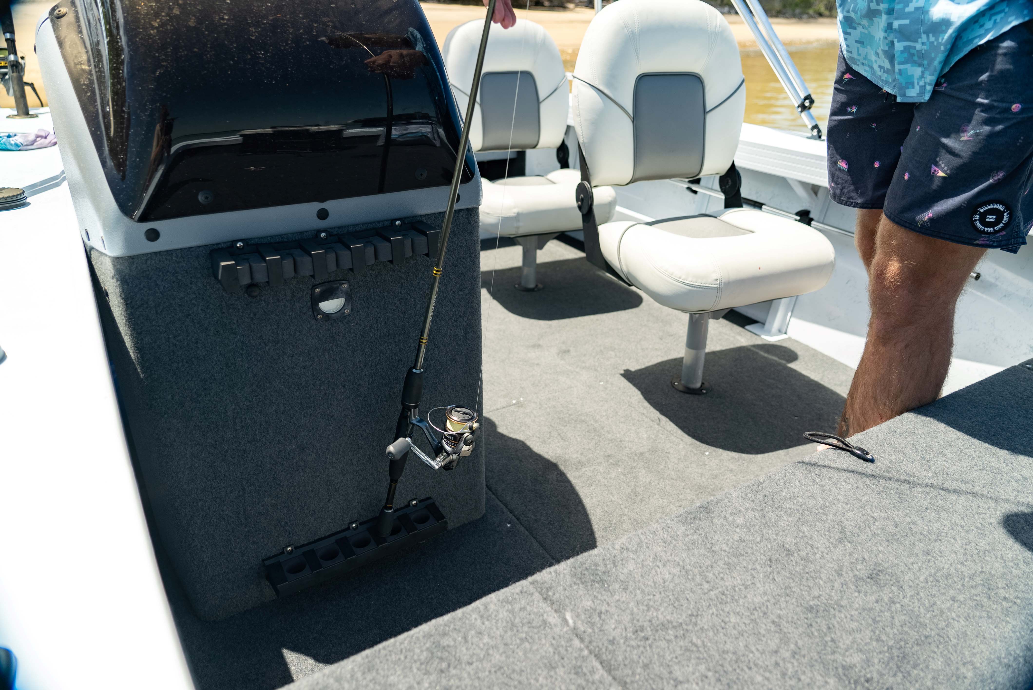a black storage console and a two white spacious seats in a small boat