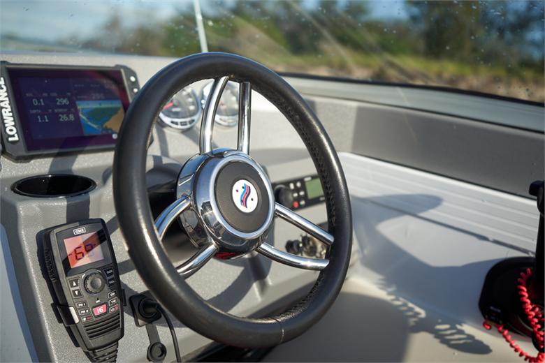 black steering wheel for boat with a radio and a fish finder